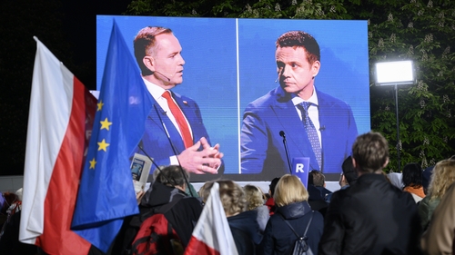 People in Warsaw watch presidential candidates Karol Nawrocki (L) and Rafal Trzaskowski debate live on public broadcaster TVP on 12 May