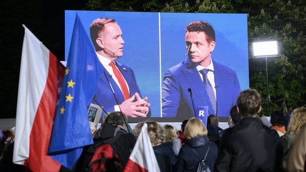 People in Warsaw watch presidential candidates Karol Nawrocki (L) and Rafal Trzaskowski debate live on public broadcaster TVP on 12 May