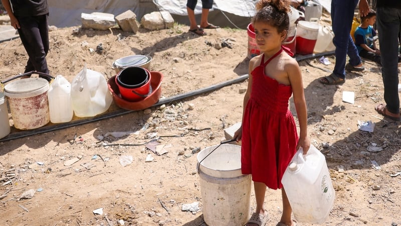 A girl holds plastic containers as displaced Palestinians collect water at a camp in Gaza City