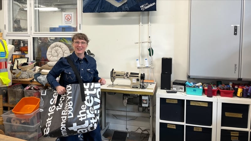 Arran Murphy, manager of Rediscover Fashion showcasing a bag repurposed from a banner