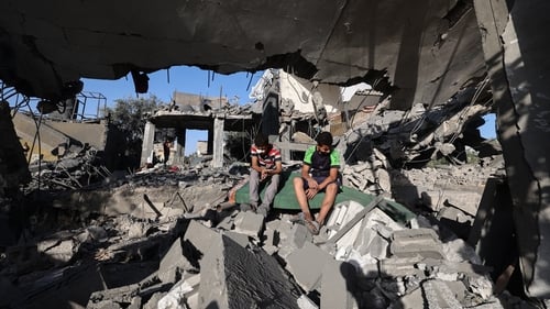 Palestinian boys sit on the rubble of a house targeted in an Israeli strike on the Nuseirat camp for refugees in central Gaza