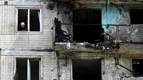 A man looks out of the window of his apartment after it was damaged in a Russian drone strike on Kyiv