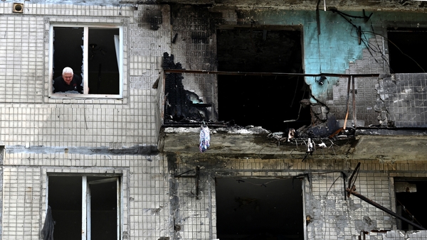 A man looks out of the window of his apartment after it was damaged in a Russian drone strike on Kyiv