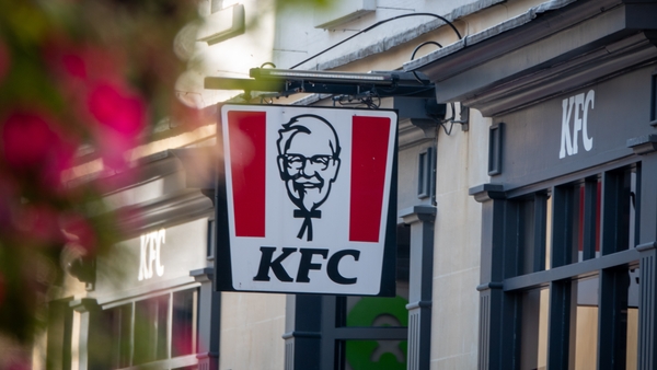 BATH, UNITED KINGDOM - SEPTEMBER 28: The sun shines on the logo of Colonel Sanders, founder of the Kentucky Fried Chicken fast food restaurant KFC, on September 28, 2024 in Bath, England. American fast food restaurant chain KFC (Kentucky Fried Chicken), s