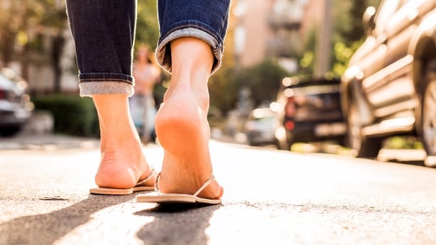 Woman wearing FlipFlops walking down the street on a sunny summer day- closeup of the feet