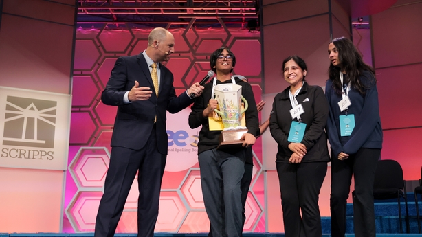 NATIONAL HARBOR, MARYLAND - MAY 29: Faizan Zaki (C), 13, of Dallas, Texas holds the Scripps Cup while being interviewed by E. W. Scripps Company CEO Adam Symson (L) alongside family after winning in the 21st round of the 2025 Scripps National Spelling Bee at the Gaylord National Resort and Conventio