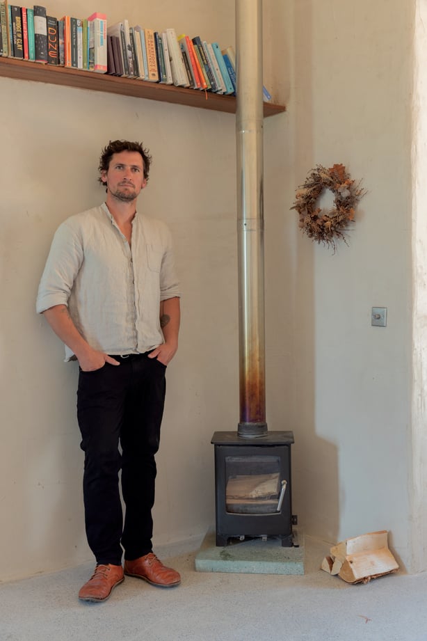 Harrison Gardner standing next to a wood stove