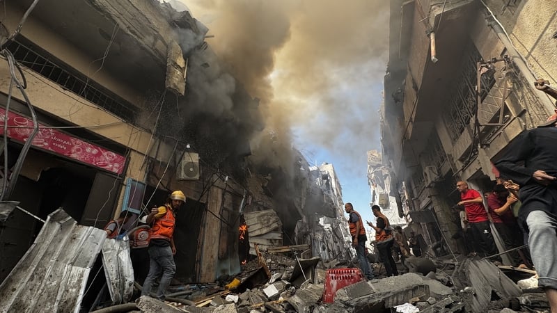 Firefighting teams extinguish a blaze after an Israeli attack struck a house and several commercial shops in Gaza City