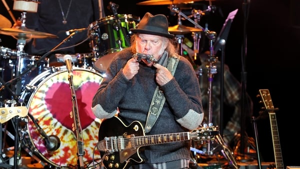 Neil Young playing a guitar on a stage