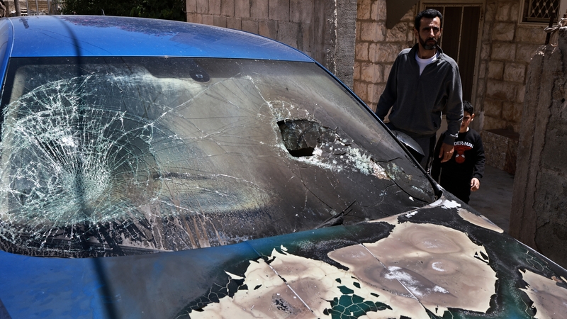 A Palestinian resident of Rammun village north east of Ramallah stands next to a car damaged by Israeli settlers