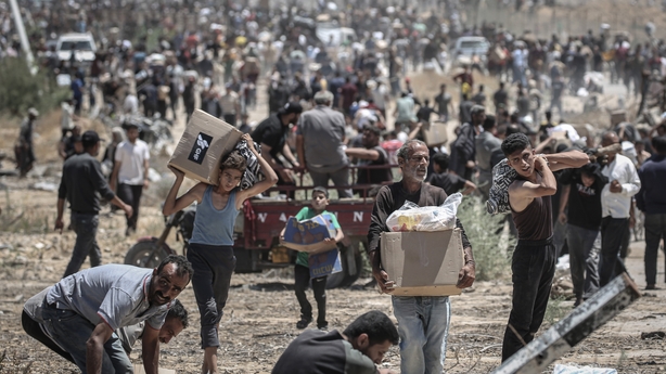 Palestinians move boxes of humanitarian aid collected from a distribution center in the Netzarim Corridor, central Gaza Strip, on Thursday, May 29, 2025. The US and Israel-backed Gaza Humanitarian Foundation says it opened a fourth distribution site and three of its four sites were fully operational