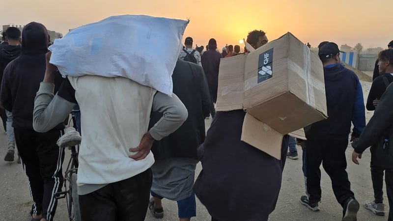 A young person carries an empty box of relief supplies from the Gaza Humanitarian Foundation earlier in the year