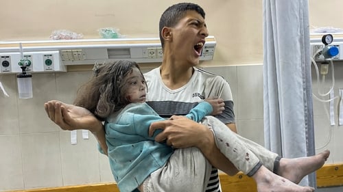 A Palestinian man carries a girl at the Nasser hospital after strikes hit displacement tents in Khan Younis