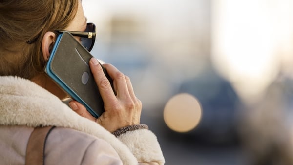 Headshot of elegant woman walking down the city street and talking with a friend over the phone.
