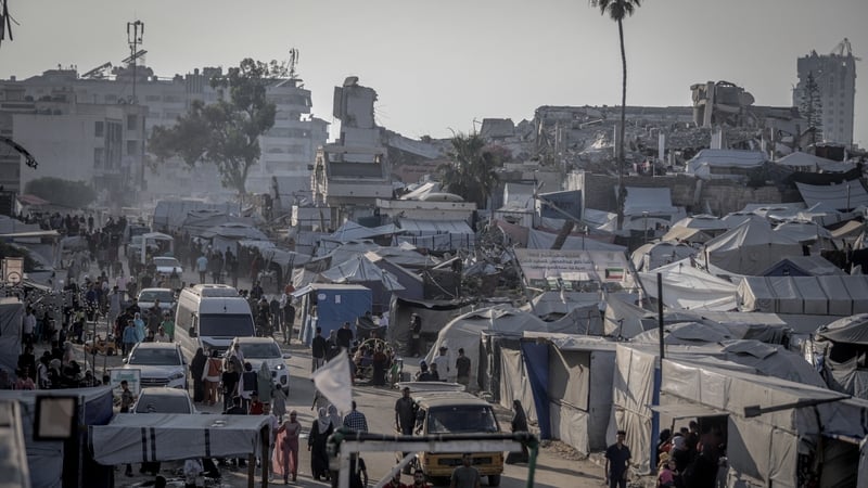 Displaced Palestinians gather among makeshift tents and small market stalls set up amid rubble in central Gaza