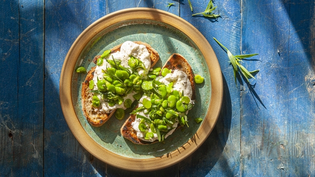 a plate of broad beans on toast on a blue table