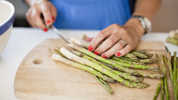 a person cutting asparagus on a cutting board