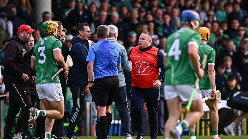 Referee Thomas Walsh is surrounded by members of both management teams at the break