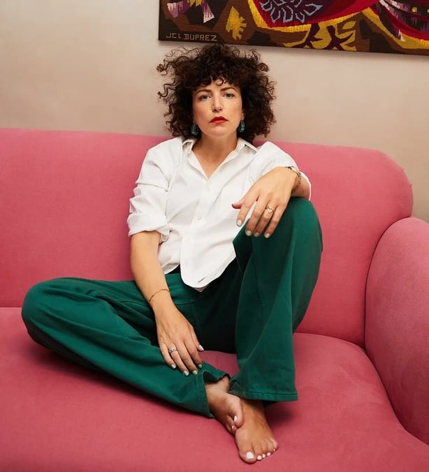 Annie Mac sitting on a couch barefoot