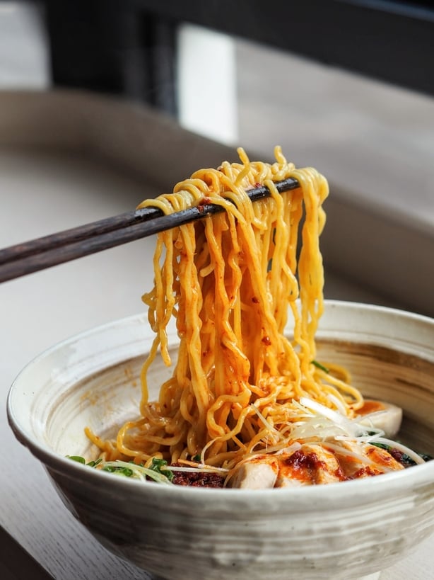 a bowl of noodles with chopsticks