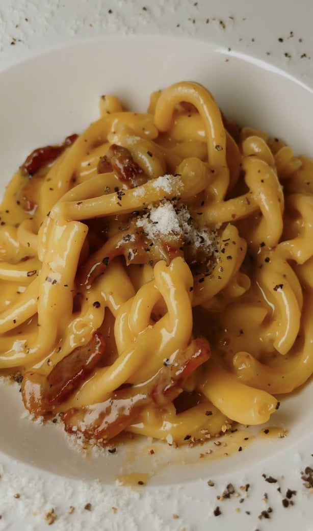 a plate of pasta with bacon and cheese