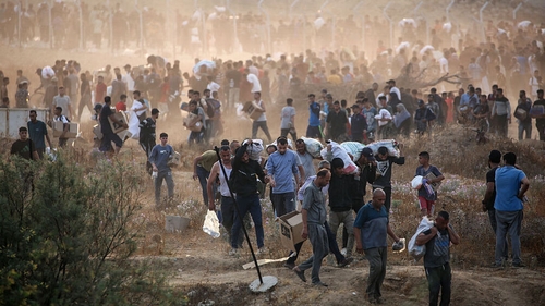 People carry relief supplies from the Gaza Humanitarian Foundation, as displaced Palestinians return from an aid distribution centre in central Gaza