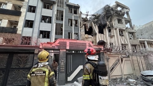 First-responders gather outside a building that was hit by an Israeli strike in Tehran
