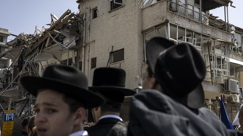 Ultra-Orthodox Jewish men look on at a site in Tel Aviv hit by a missile fired from Iran this morning