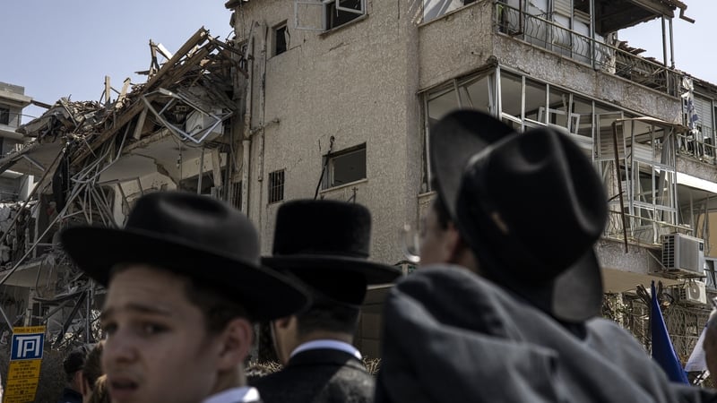 Ultra-Orthodox Jewish men look on at a site in Tel Aviv hit by a missile fired from Iran this morning