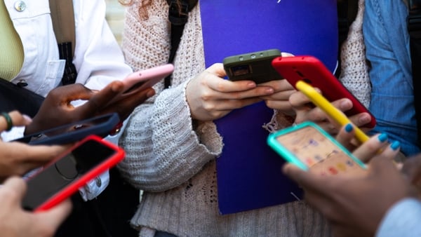 Close up of young college students hands holding mobile phones. Teenagers addicted to smartphones and technology. Group of friends sharing content on social media. Technology concept.