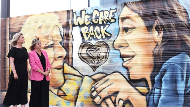 a group of women standing in front of a mural