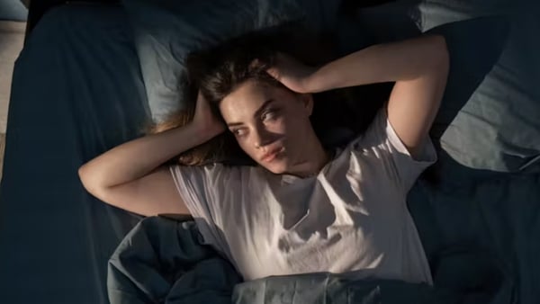 a woman lying in bed with her hands on her head