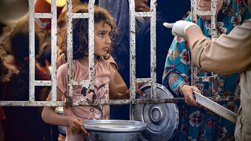 A young child queues to receive a hot meal at a distribution point in Gaza