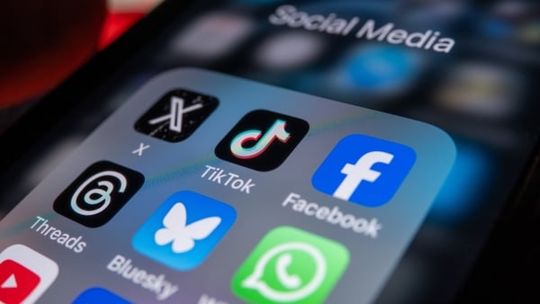 A photo illustration shows a smartphone screen displaying the logo of social media app TikTok, beside the logo of 'X' and the logo for Facebook