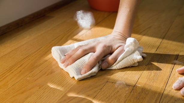 a hand wiping a hardwood floor
