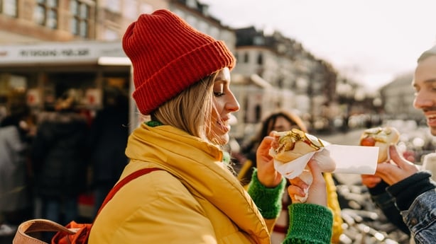 Photo of smiling friends trying out local street food on their trip
