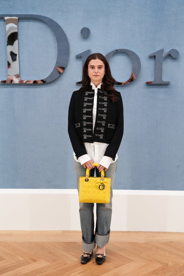 Alison Oliver wearing a black military-inspired jacket, a white shirt and jeans
