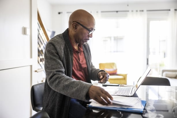 Senior man using laptop and paying bills at home