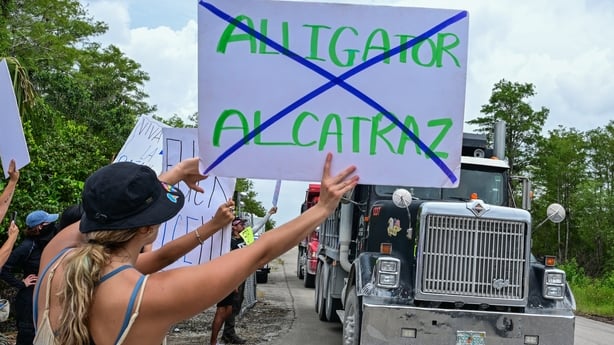 Trucks leave the Dade-Collier Transition and Training Airport as demonstrators protest the construction of an immigrant detention center, dubbed "Alligator Alcatraz," in the Everglades near Ochopee, Florida, on June 28, 2025. Florida began construction this week on a detention center surrounded by f