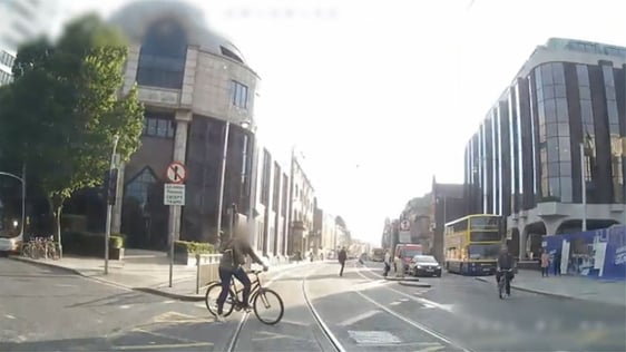 A cyclist on the Luas track as a tram approaches on the Red Line, 2020.