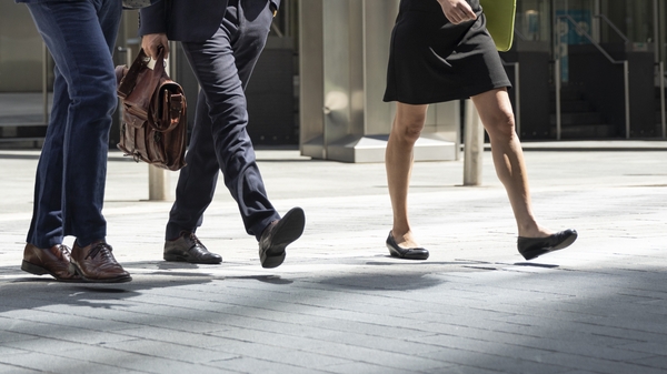 Three coworkers walking on city street with laptop discussing project
