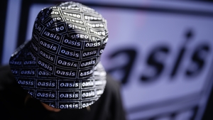 An Oasis fan wears a bucket hat with the band logo