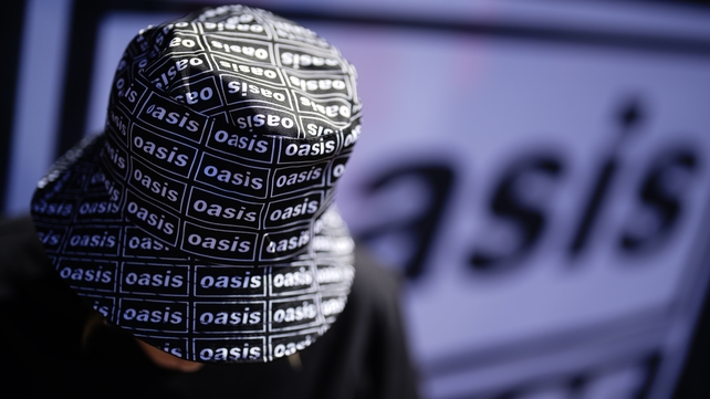 An Oasis fan wears a bucket hat with the band logo