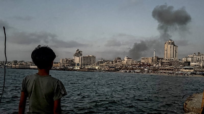 A child watches on as smoke billows following an Israeli attack on the Al-Shati refugee camp in Gaza