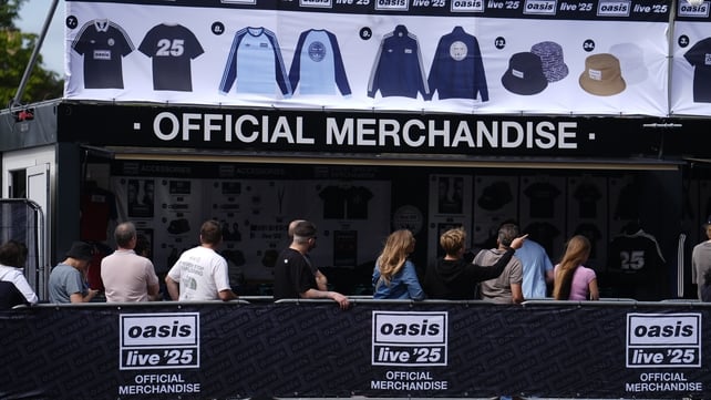 Oasis fans stand in the queue for the official merchandise stand outside the Principality Stadium, Cardiff