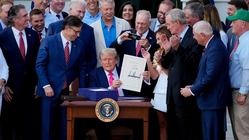 US President Donald Trump displays the signed bill during a ceremony for the One Big Beautiful Bill Act on the South Lawn of the White House