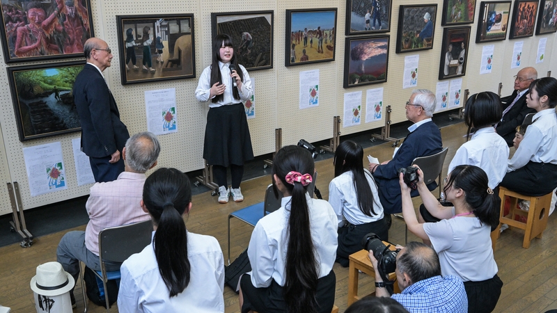 Atomic bomb survivor Hidetaka Takiguchi listens to a student as she speaks during a preview of the artwork Motomachi High School in Hiroshima