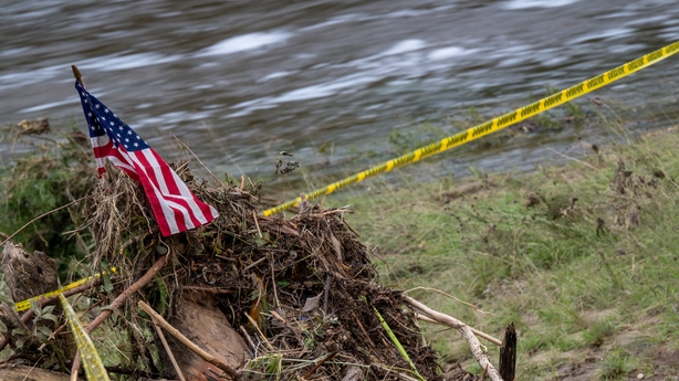 KERRVILLE, TEXAS - JULY 06: An America flag is stationed over caution tape on the banks of the Guadalupe River on July 06, 2025 in Kerrville, Texas. Heavy rainfall caused severe flooding along the Guadalupe River in central Texas, leaving more than 70 people reported dead. (Photo by Brandon Bell/Get