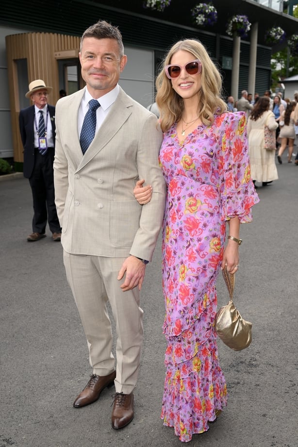 A man wearing a pale beige suit with a woman in a pink and purple floral dress
