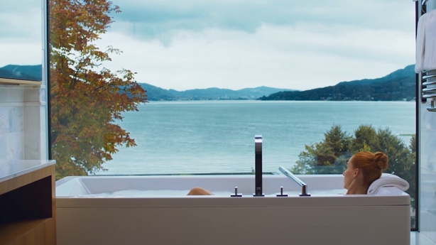 a person in a bathtub overlooking a body of water